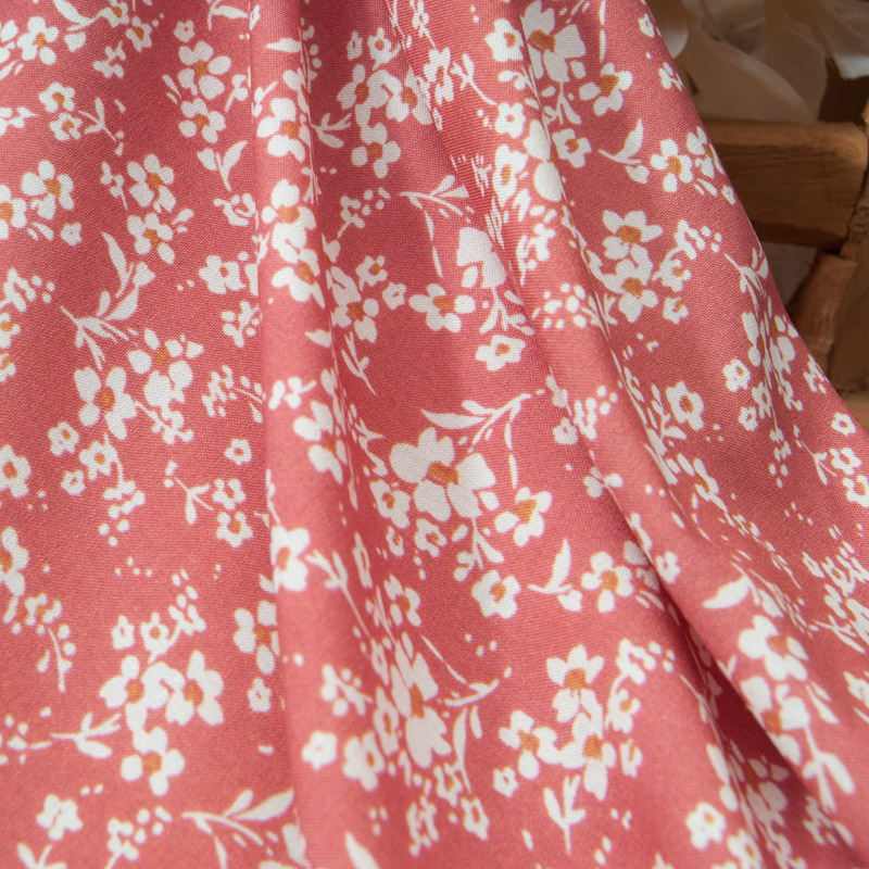 Popeline de viscose fleurie fond corail drapée en mouvement